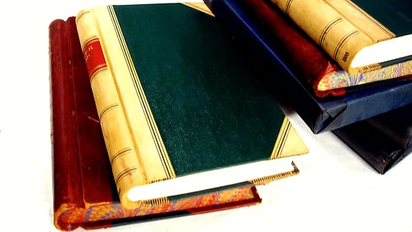 A handwritten letter on lined paper resting on a table beside a plain envelope and a pair of reading glasses