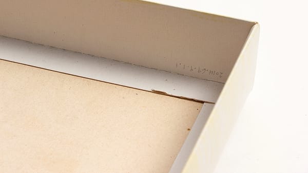 A first aid kit open on a counter with an adhesive bandage wrapper and a paper form beside it