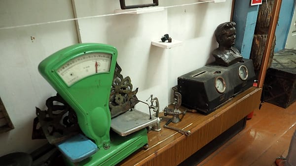 A stack of cylindrical calibration weights beside a stainless steel counter scale in a workshop