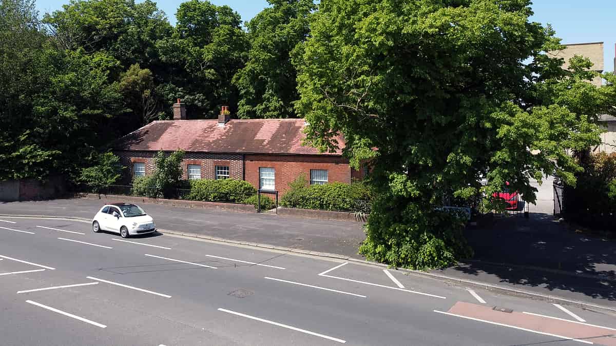 Shelves of used phones, games consoles and cameras in labeled trays behind a shop counter with a card reader